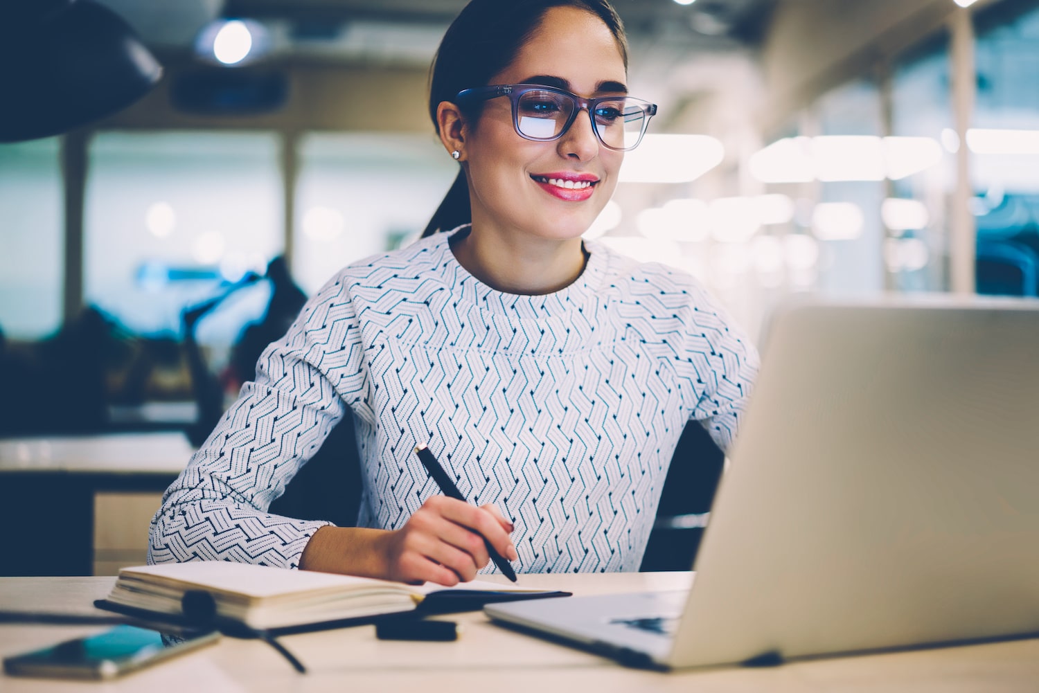 Smart young woman satisfied with learning language during online courses using netbook, smiling female student doing homework task in college library searching information via laptop computer