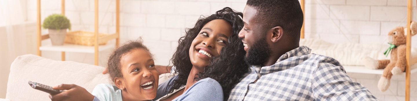 Joyful black family having fun together, relaxing on sofa at home.