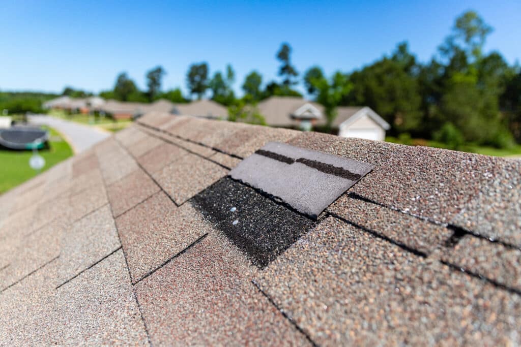 Close-up of a broken shingle on a roof, needing repair.