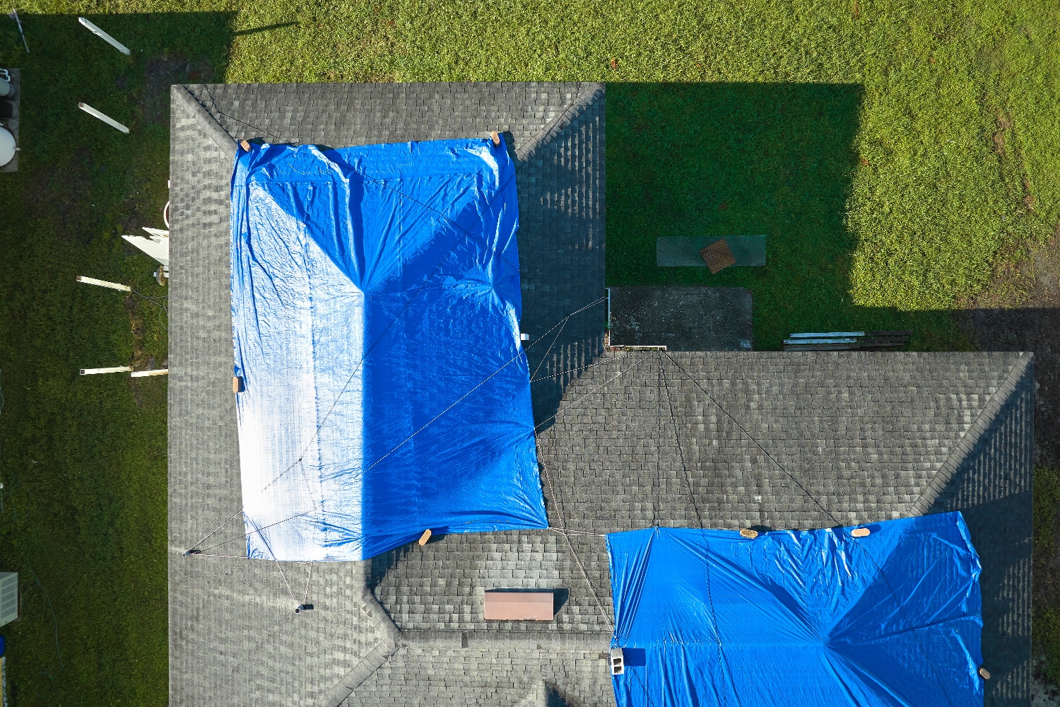 Roof covered with plastic secured by bricks for temporary weather protection