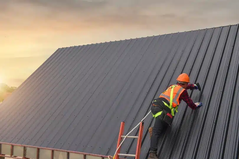 Construction worker on a metal roof in Milford