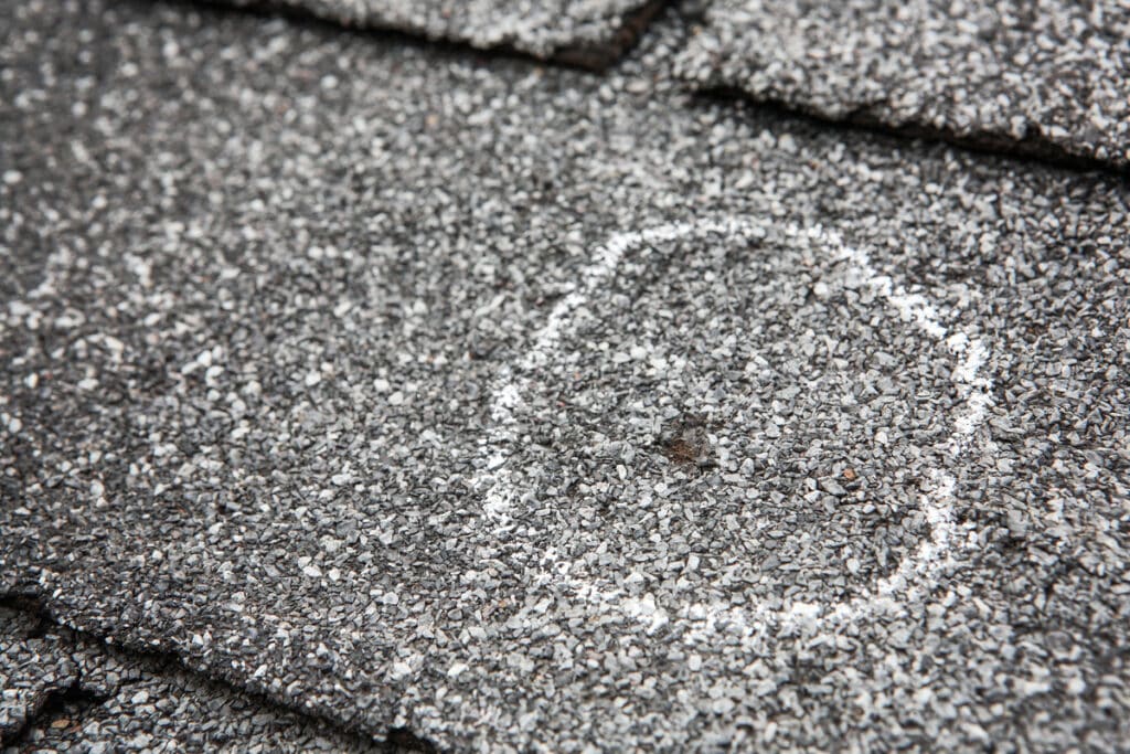 hail damage vs blistering-close up of hail damage circled in chalk on roof shingles