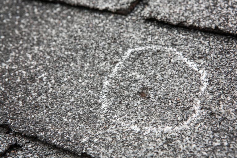 hail damage vs blistering-close up of hail damage circled in chalk on roof shingles