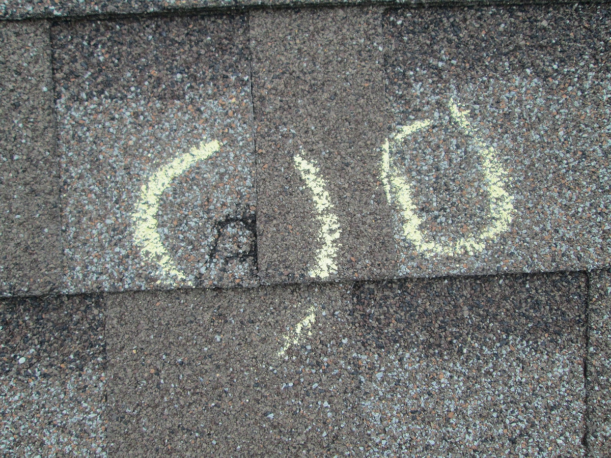 hail damage vs blistering-marks from hail indicated with chalk on roof shingles