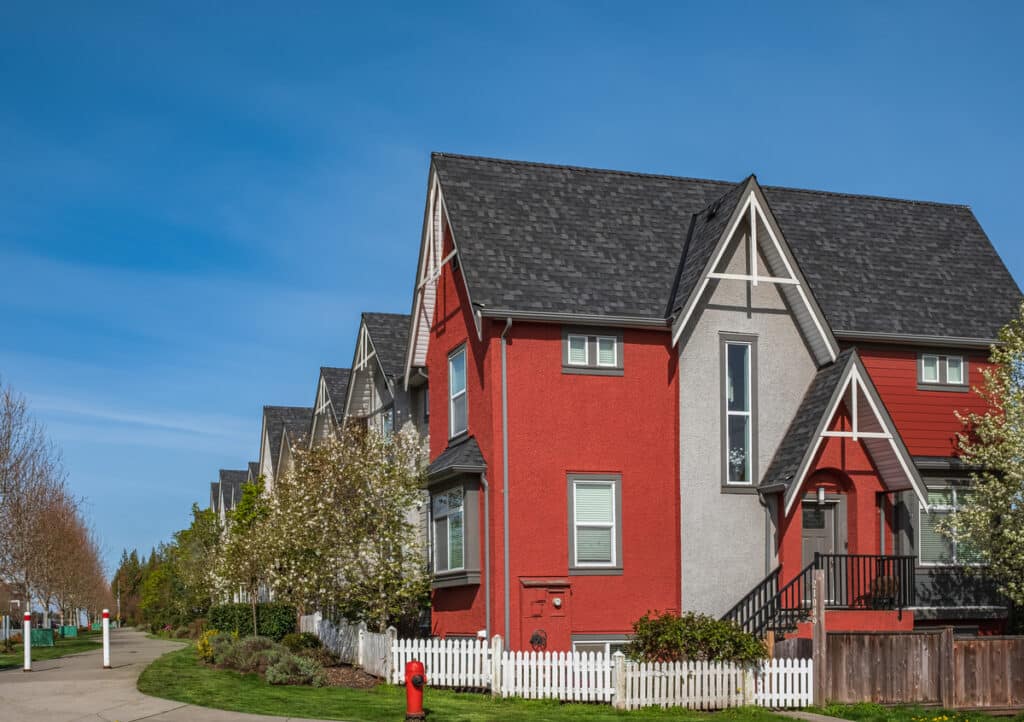 luxury asphalt shingles-neighborhood with flowering trees and white picket fences with luxury asphalt shingle roofing