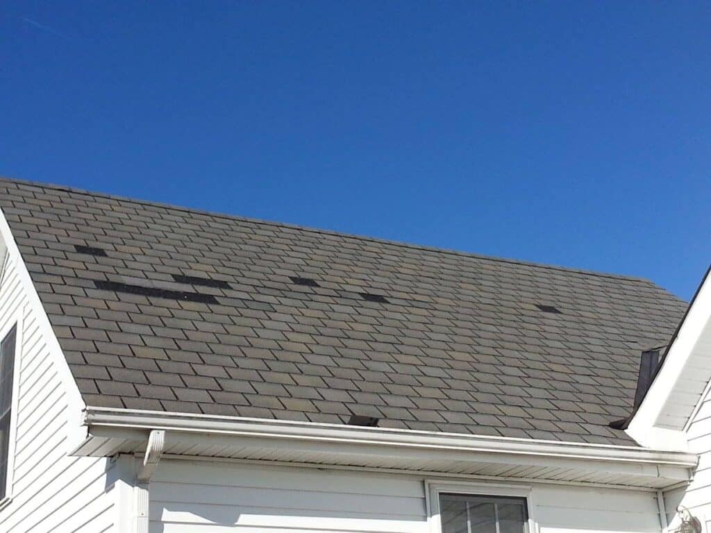 Roof missing shingles from a recent storm.